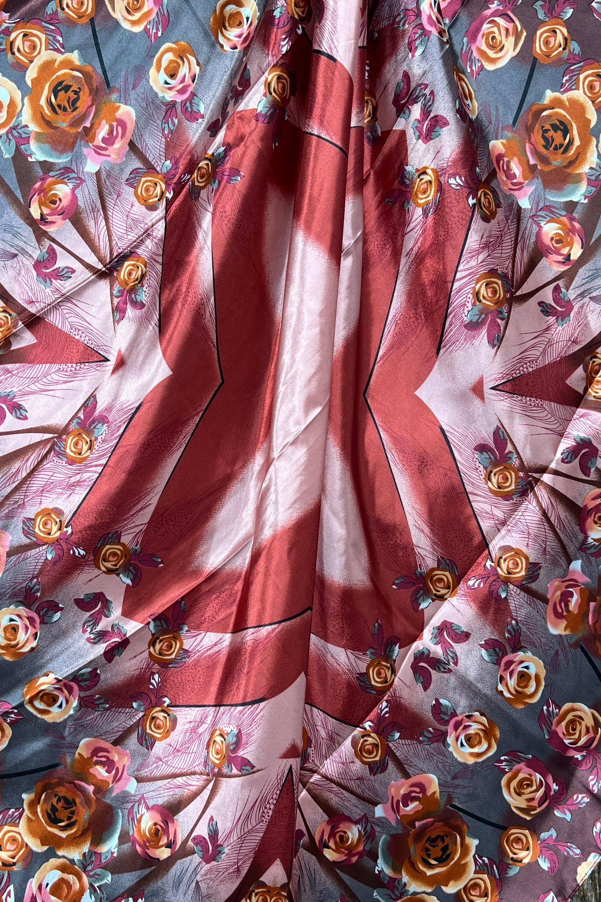 Floral fabric with a red,rust,pink and white floral pattern on a wooden surface