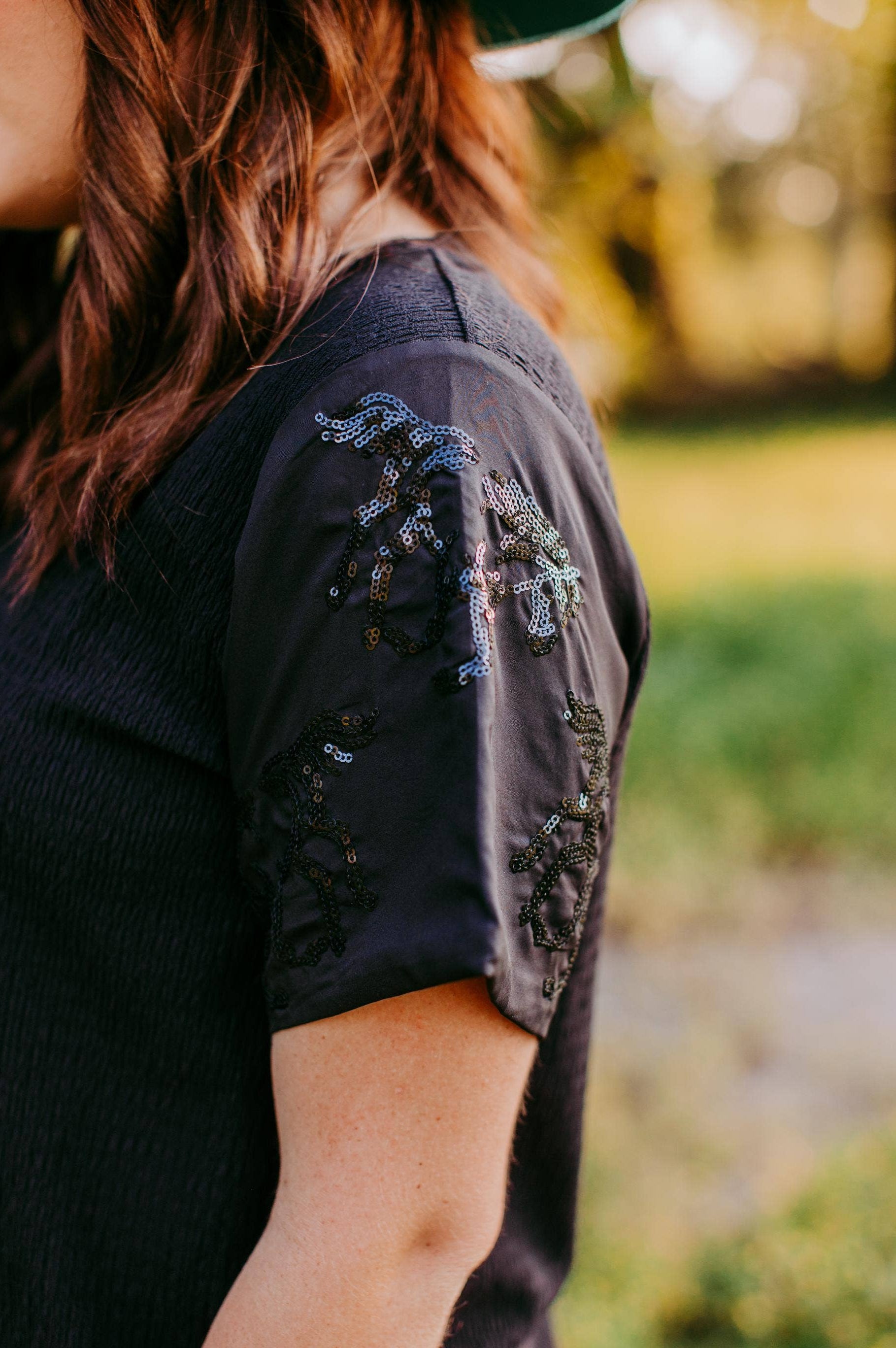 Person wearing a black top with horse sequin on sleeves