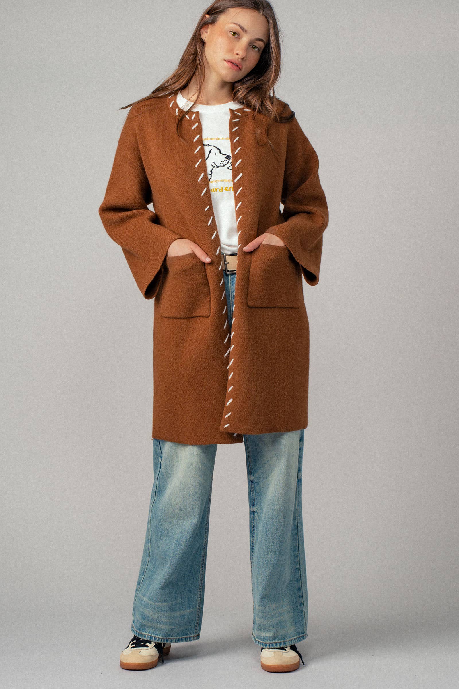 Woman wearing a brown open coat with white bold stitching trim