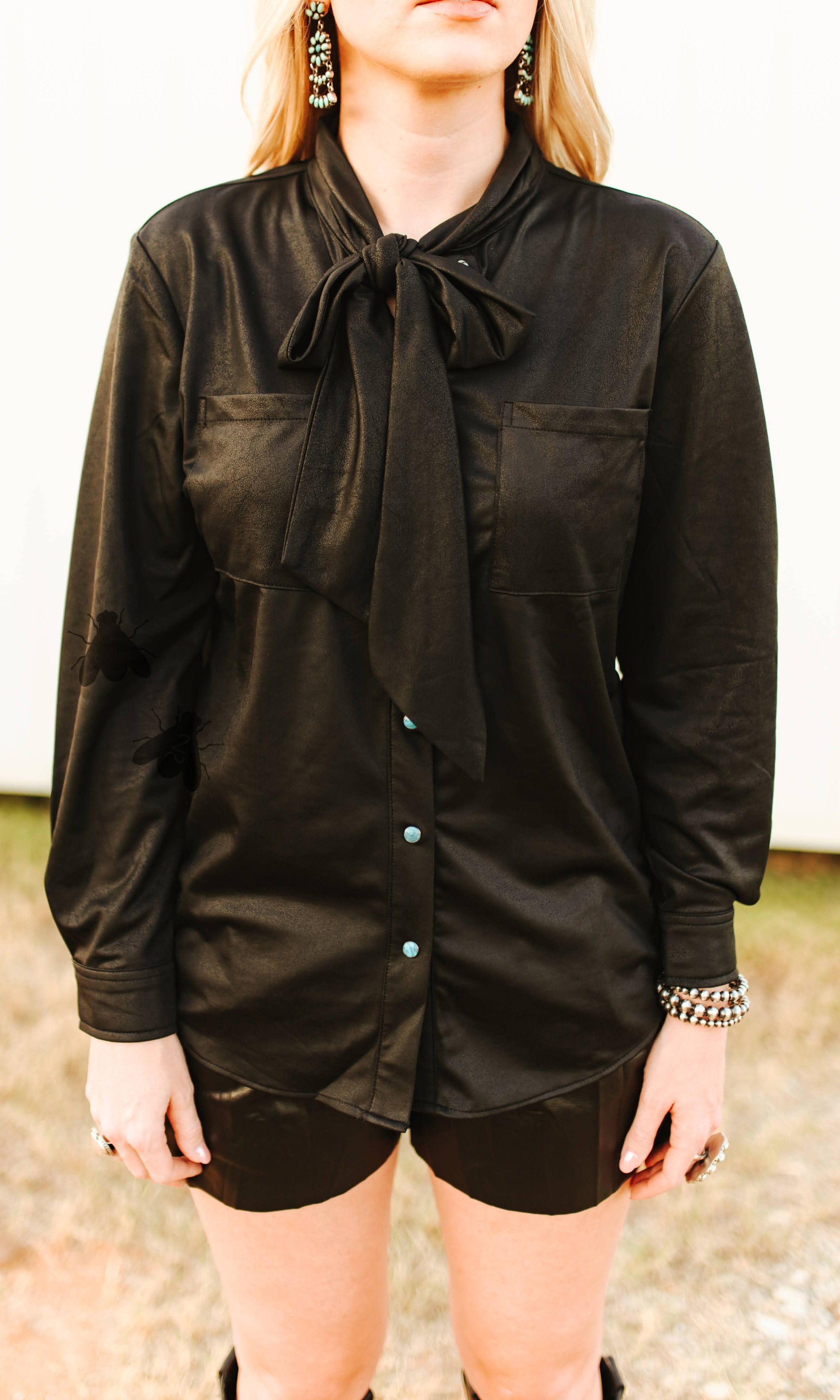 Person wearing a black long-sleeve shirt with a tie collar outdoors.