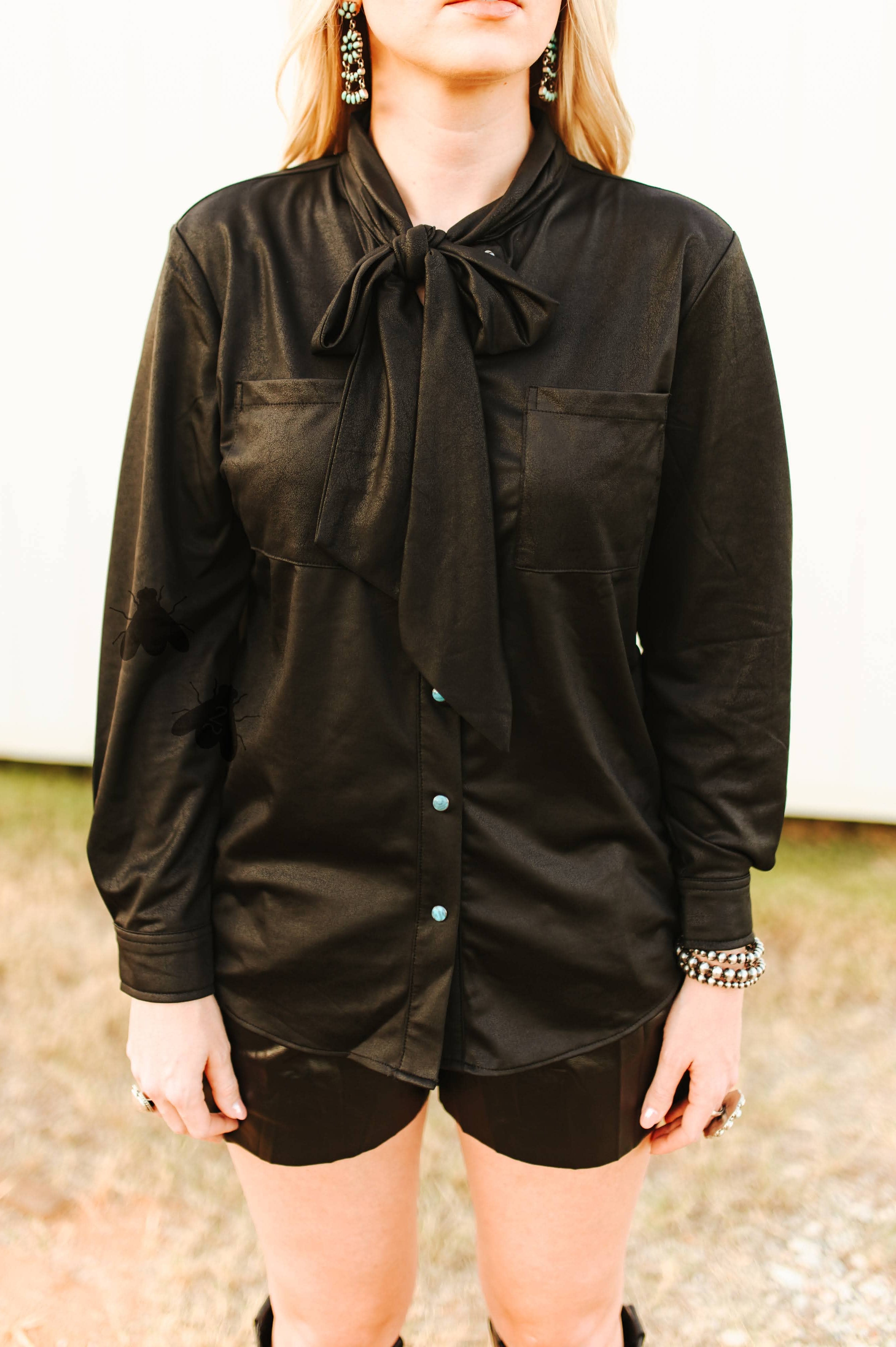 Person wearing a black long-sleeve shirt with a tie collar outdoors.