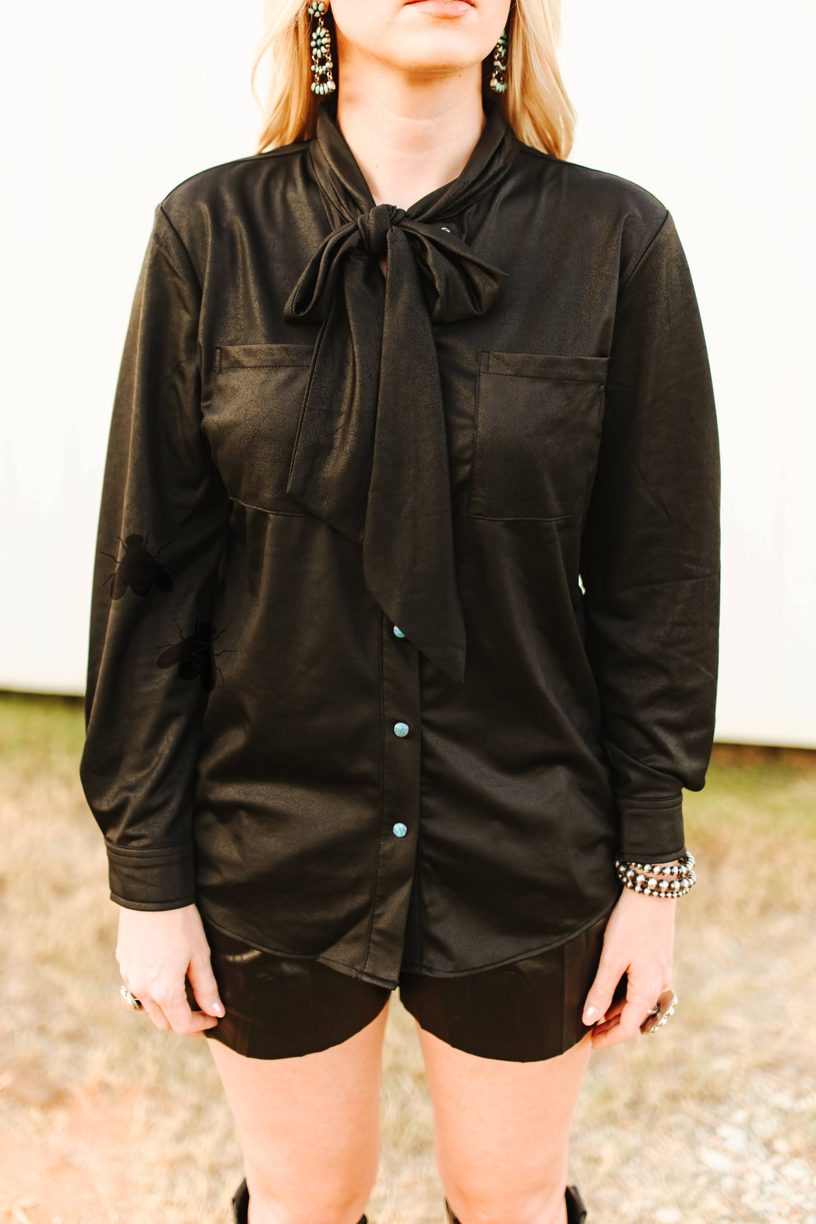 Person wearing a black long-sleeve shirt with a tie collar outdoors.