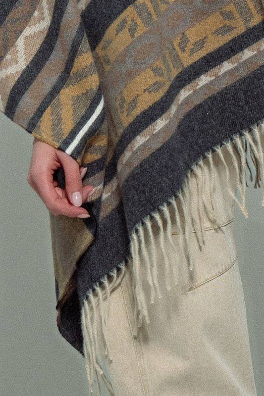 Dark gray poncho with brown and beige striped pattern and fringes on a white background