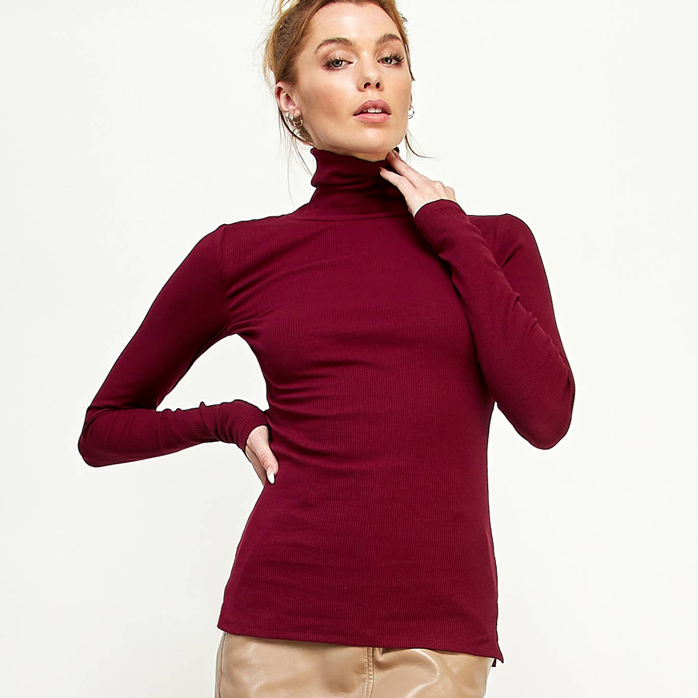 Woman wearing a burgundy turtleneck sweater on a white background