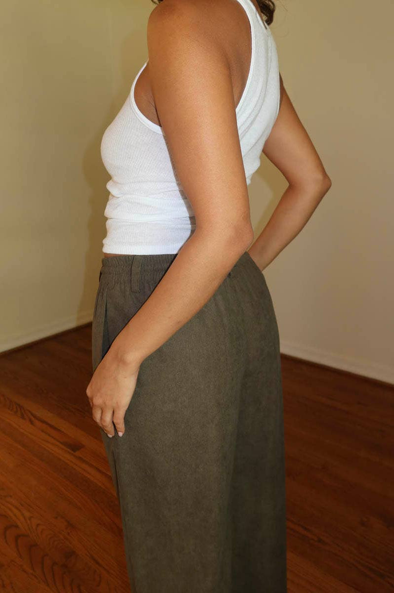 Person wearing a white top and Brown drawstring pants on a plain background