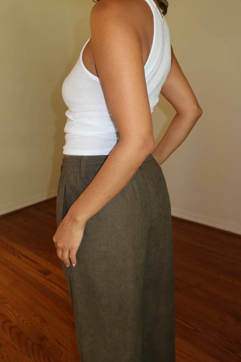 Person wearing a white top and Brown drawstring pants on a plain background