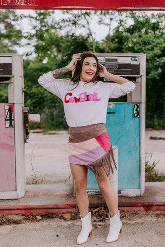 Woman posing in front of a vintage gas pump wearing a 'Cowgirl' sweatshirt.