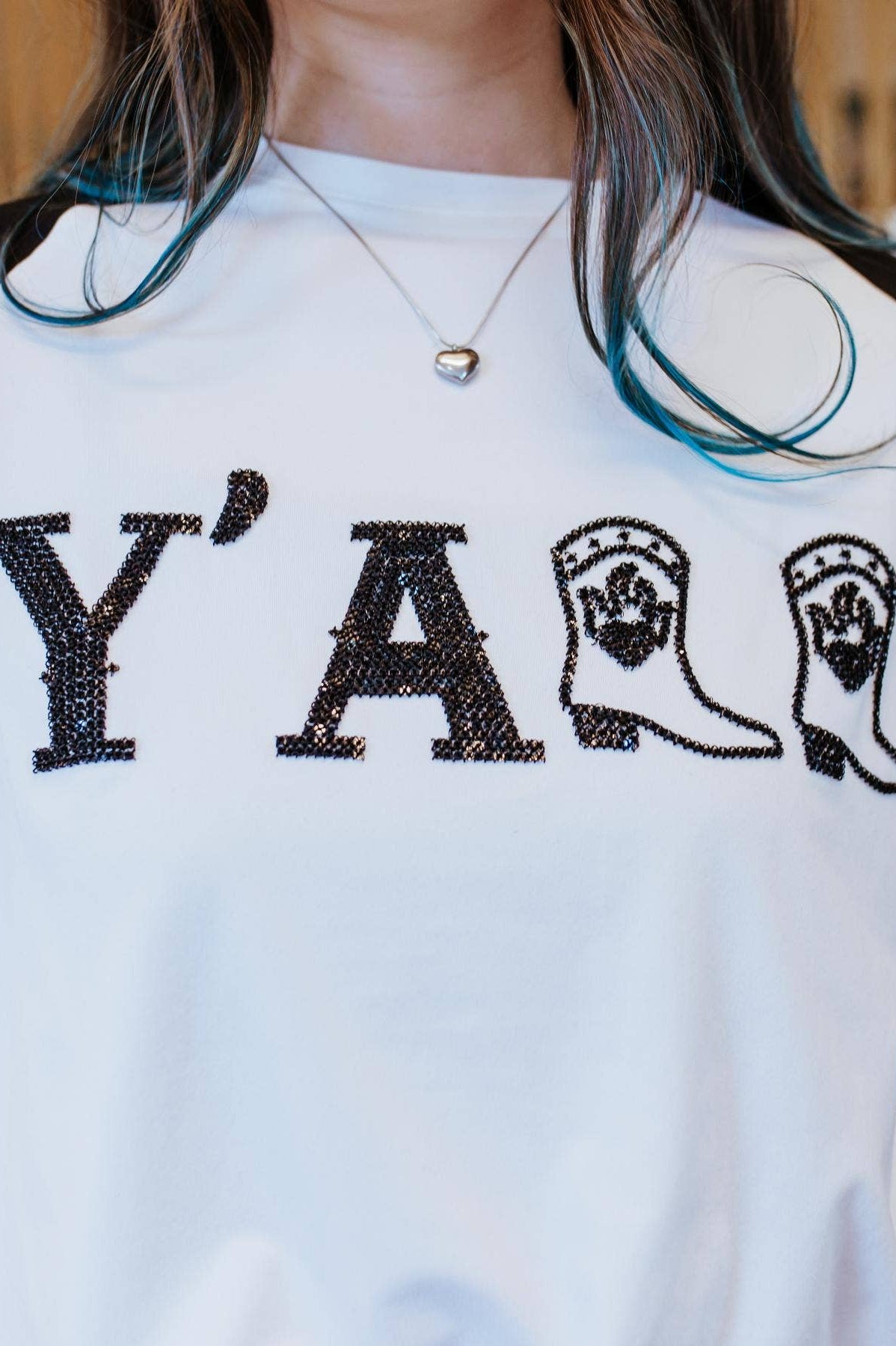 Person wearing a white t-shirt with 'Y' and cowboy boot design, standing in a staircase.