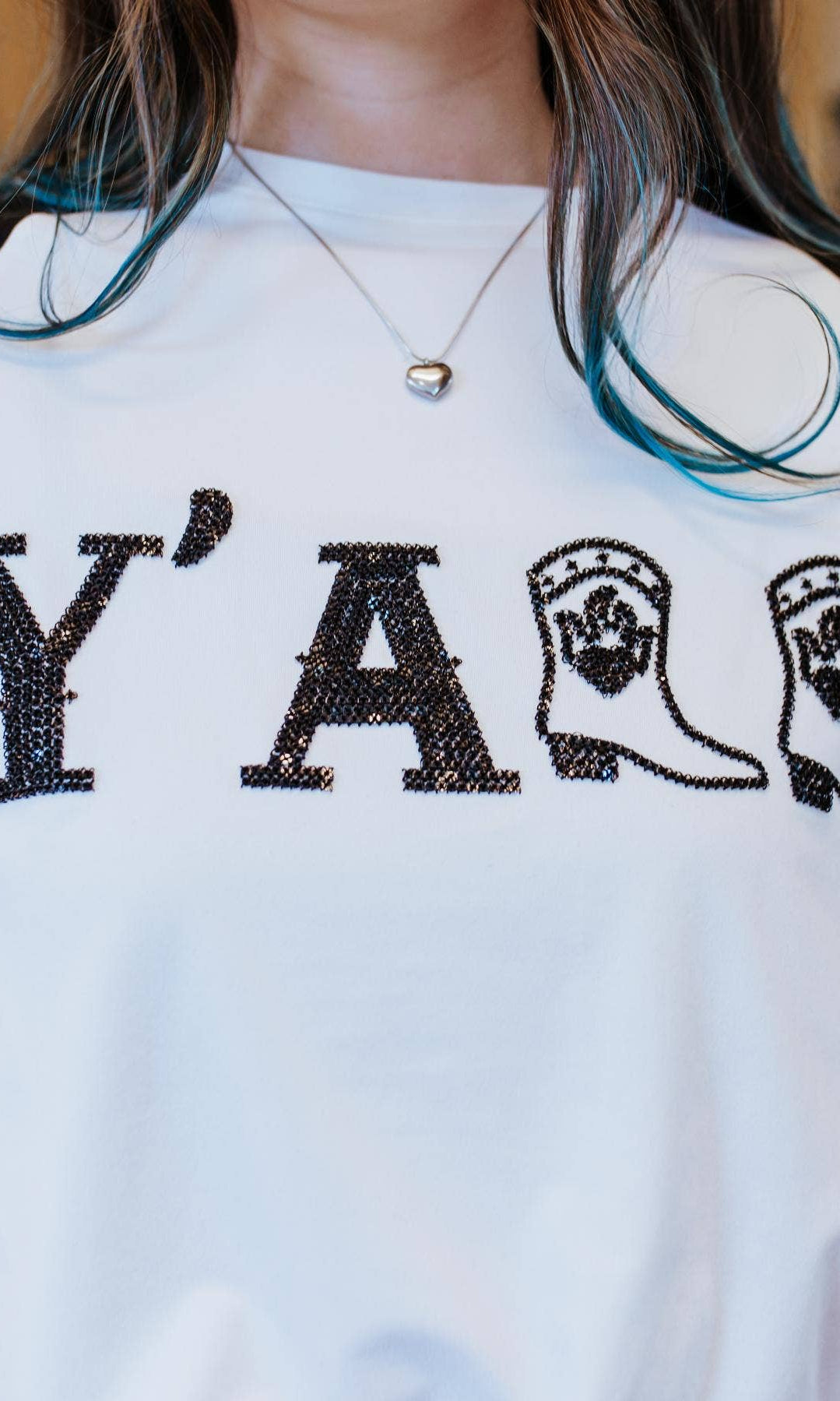 Person wearing a white t-shirt with 'Y' and cowboy boot design, standing in a staircase.
