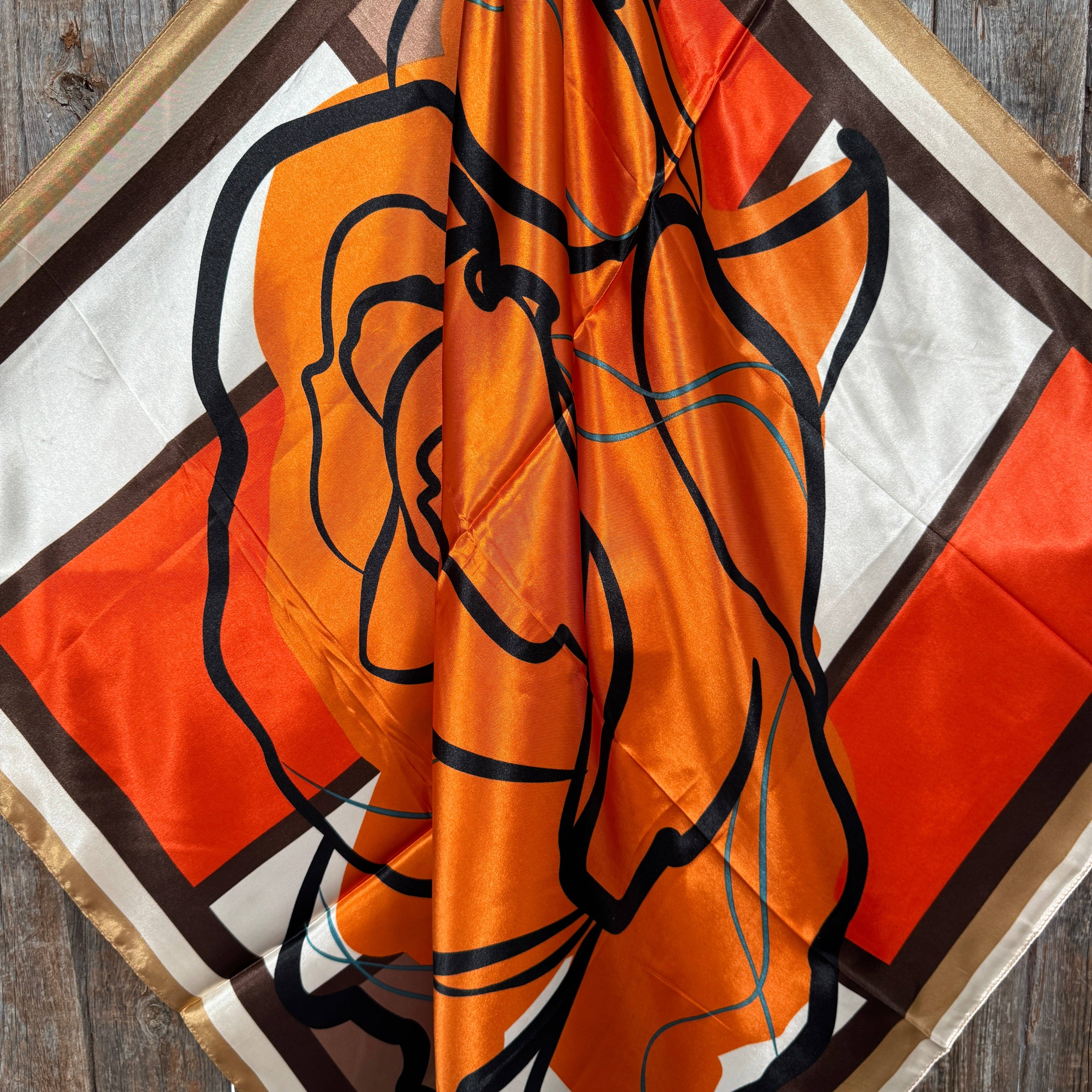 Orange scarf with black line art on a wooden surface