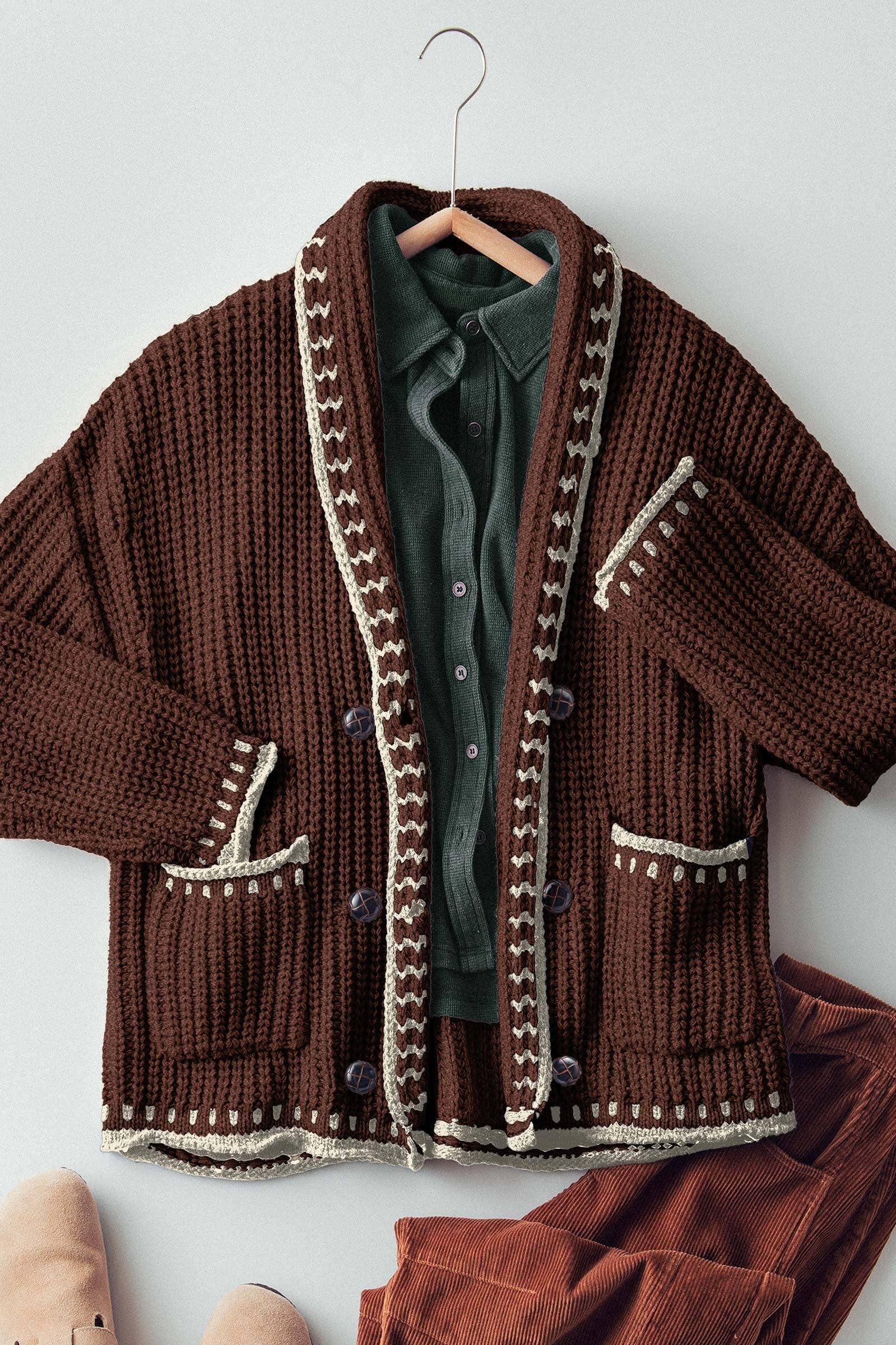 Brown knitted cardigan with decorative trim on a hanger against a white background