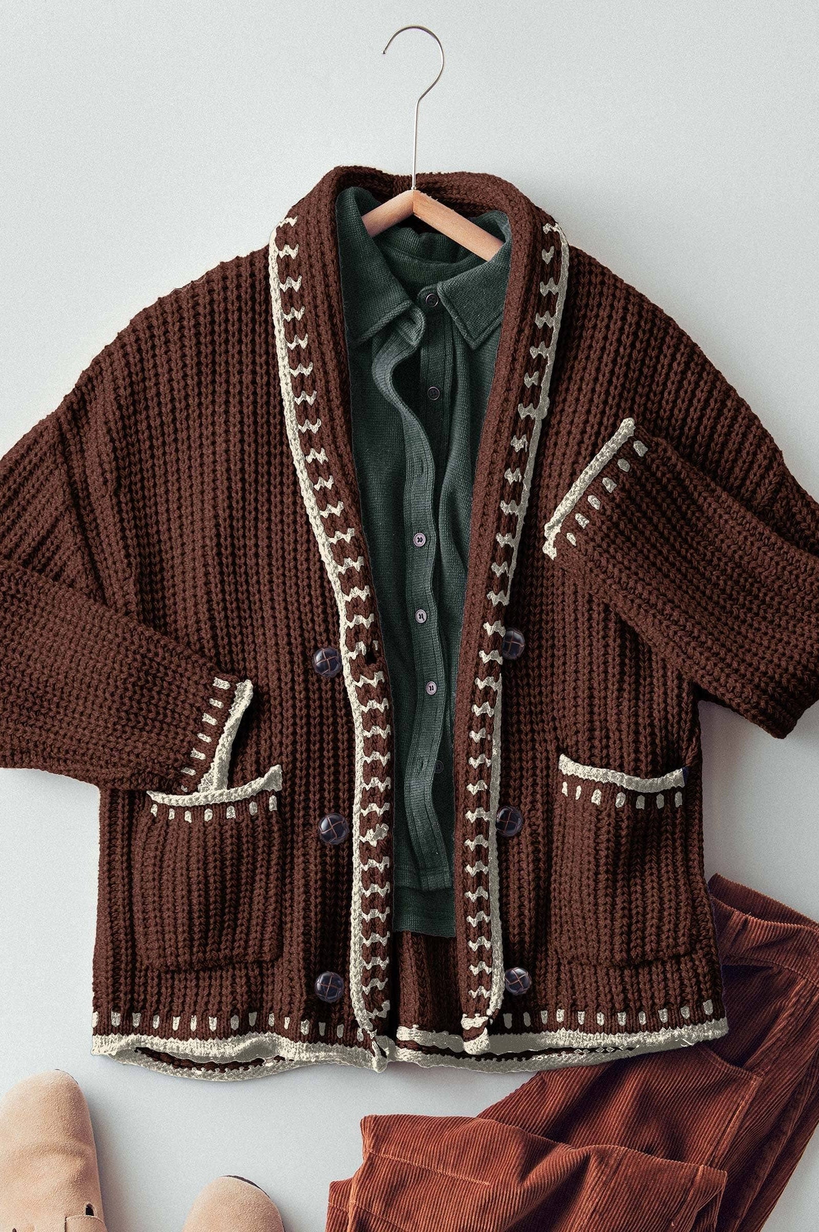 Brown knitted cardigan with decorative trim on a hanger against a white background