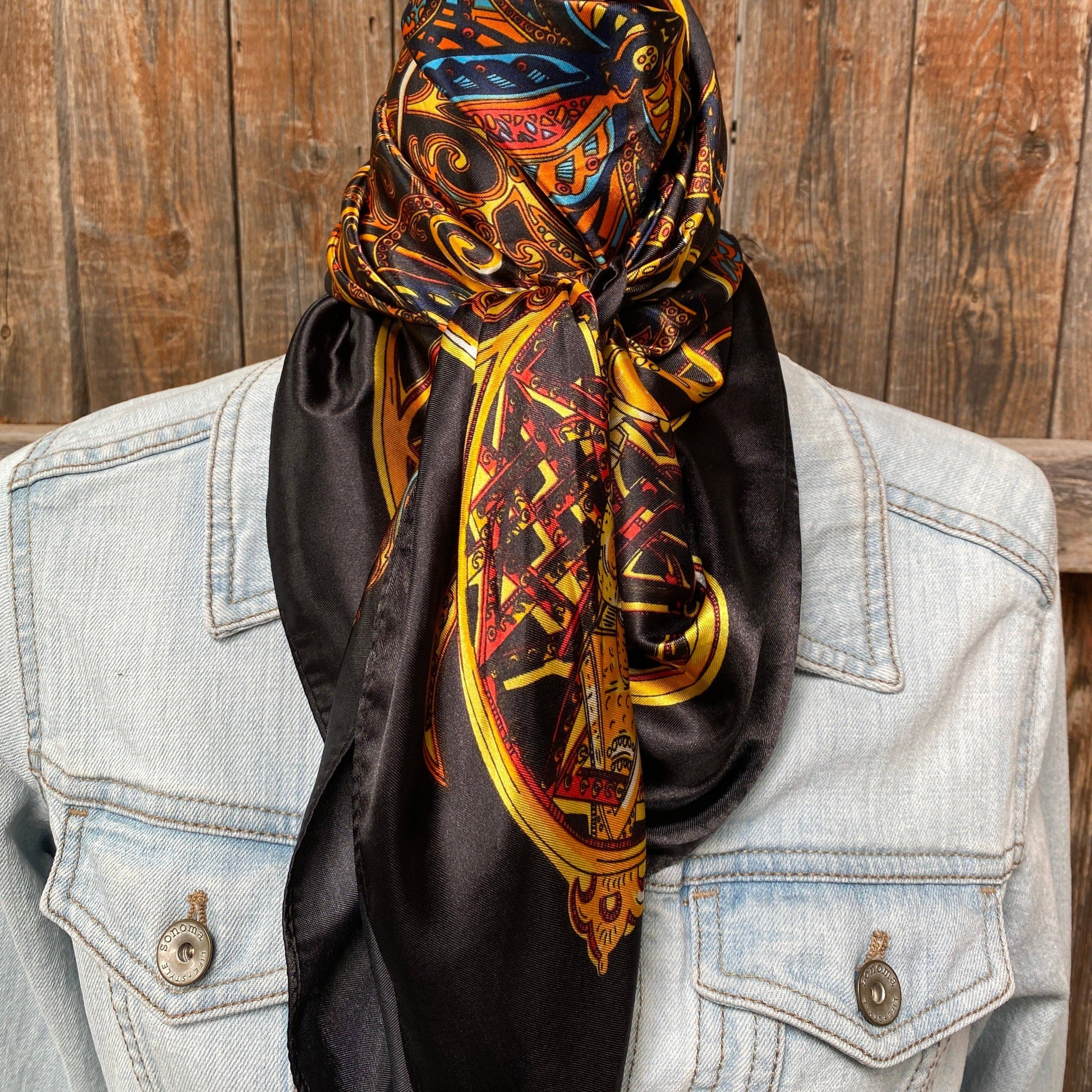 Decorative scarf with intricate patterns draped over a denim jacket against a wooden background