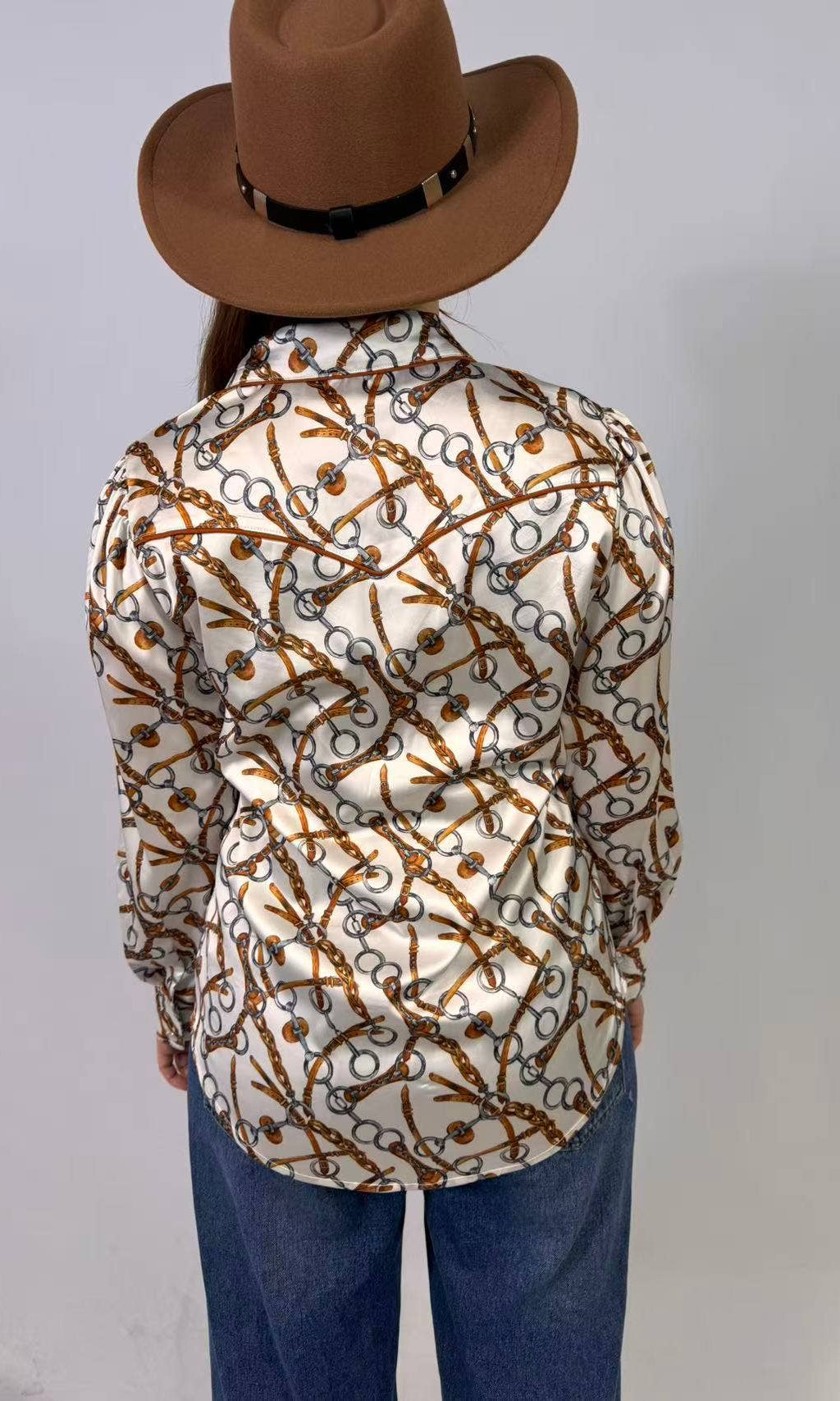 Person wearing a patterned shirt and brown hat on a plain background