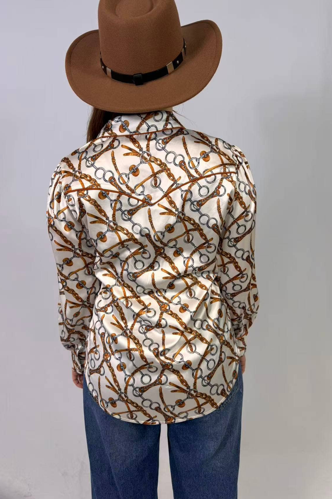 Person wearing a patterned shirt and brown hat on a plain background