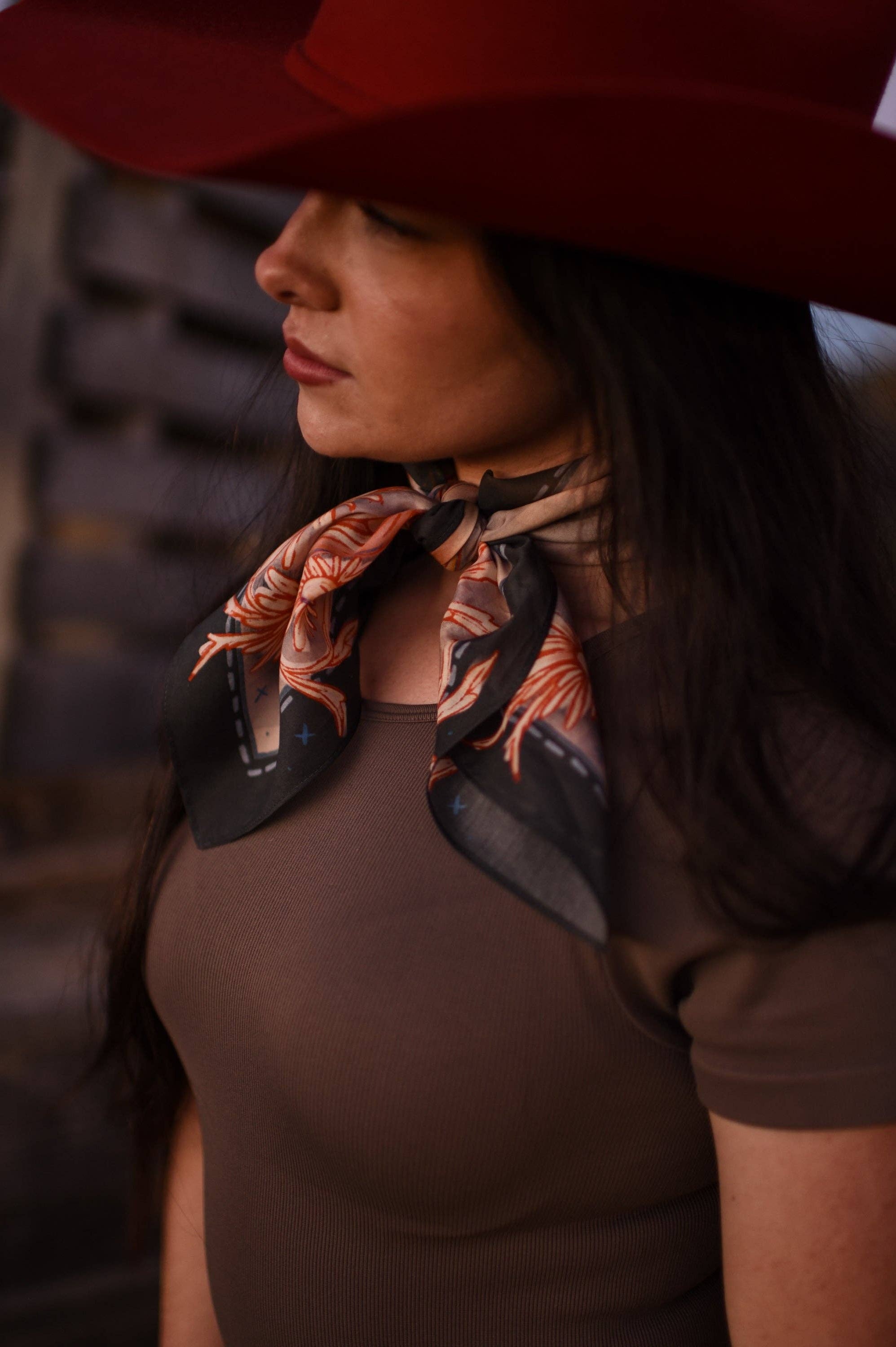 Woman wearing a red hat and brown top with a patterned scarf around her neck.