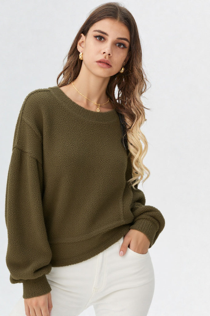 Woman in a olive round-neck textured knit oversized top with drop shoulders and long sleeves, relaxed fit