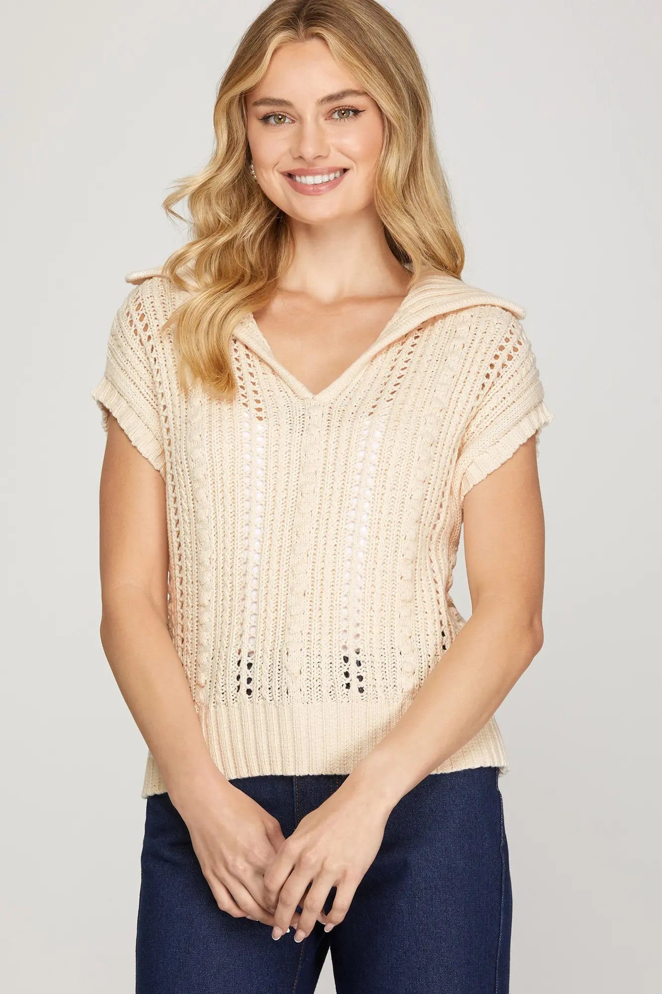 Woman wearing a beige crochet top with short sleeve and collar