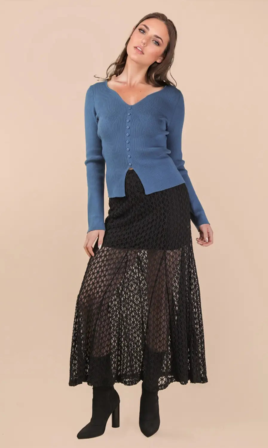 Woman wearing a blue sweater and black lace skirt on a beige background
