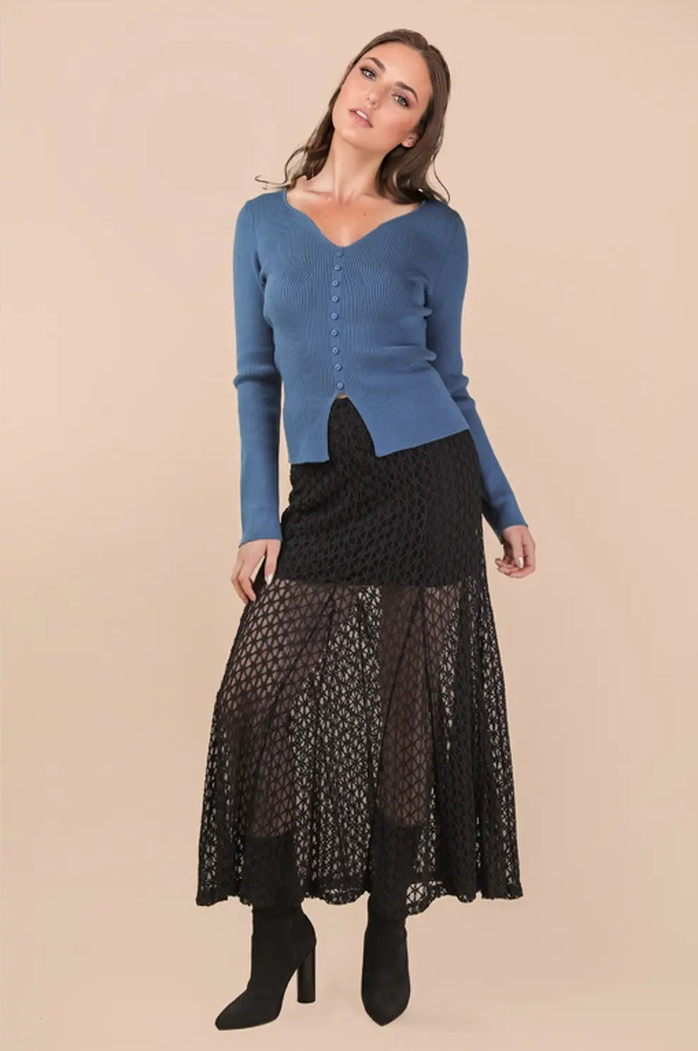 Woman wearing a blue sweater and black lace skirt on a beige background