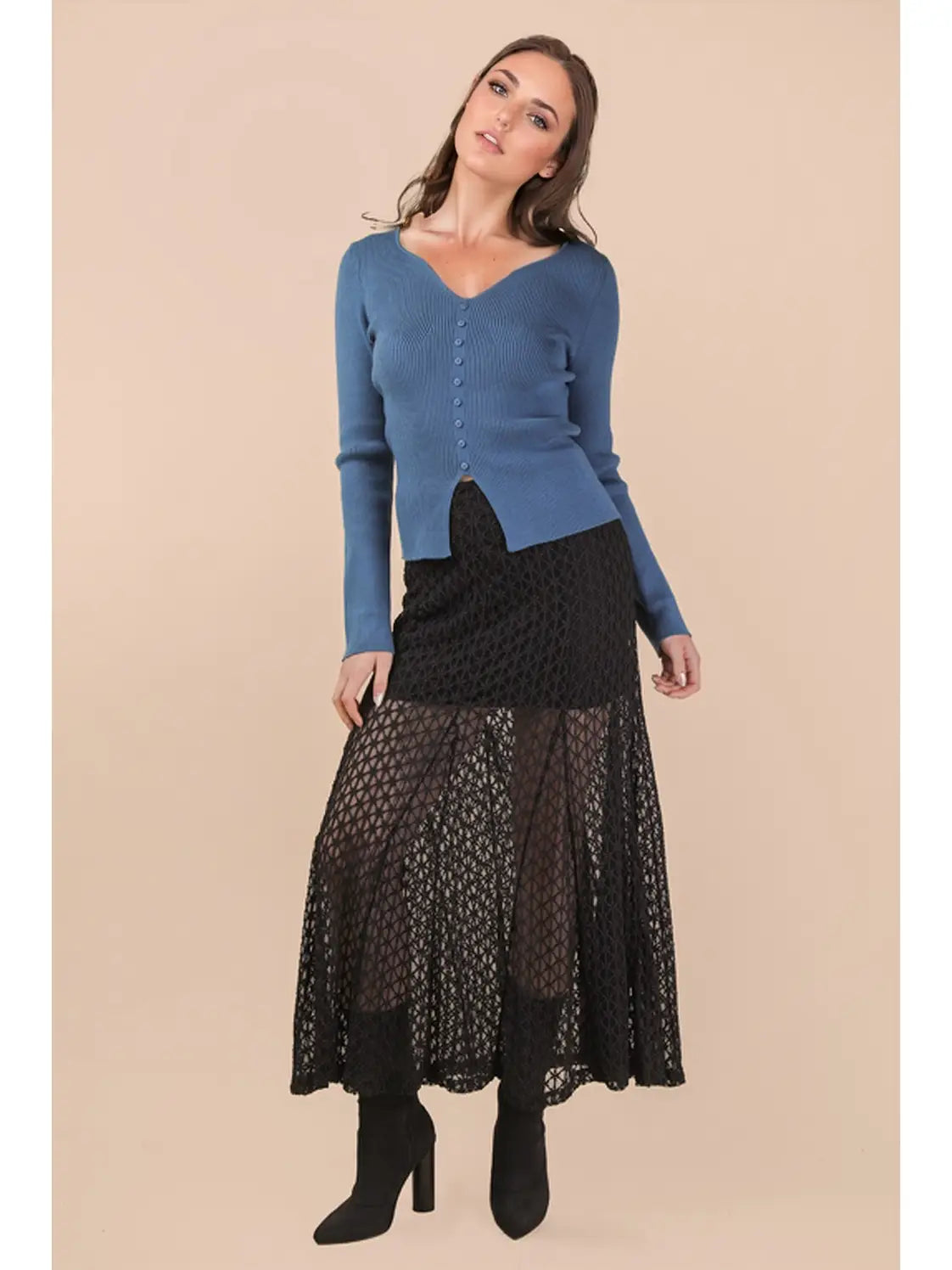 Woman wearing a blue sweater and black lace skirt on a beige background