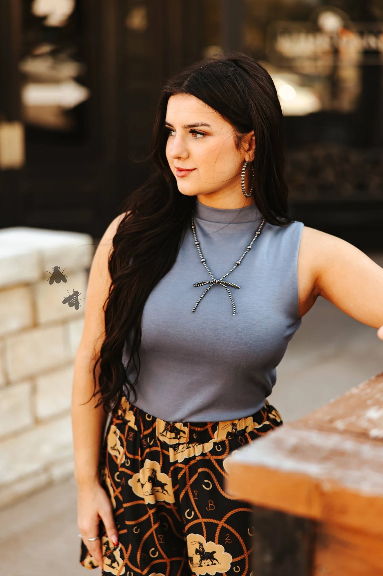 Woman wearing a sleeveless top and patterned pants with a blurred background
