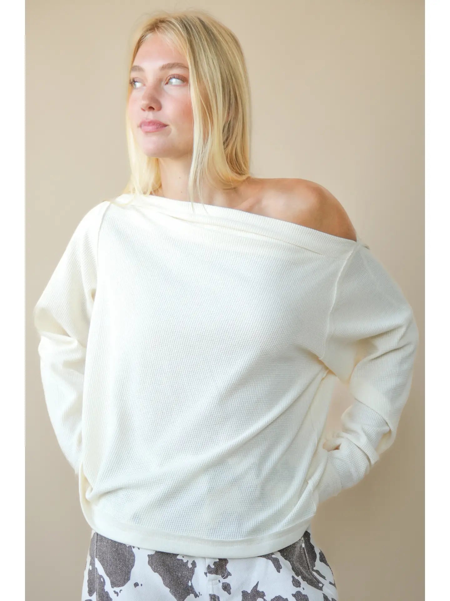 Front view of solid boat-neck cotton knit top worn slightly off-shoulder, long sleeves