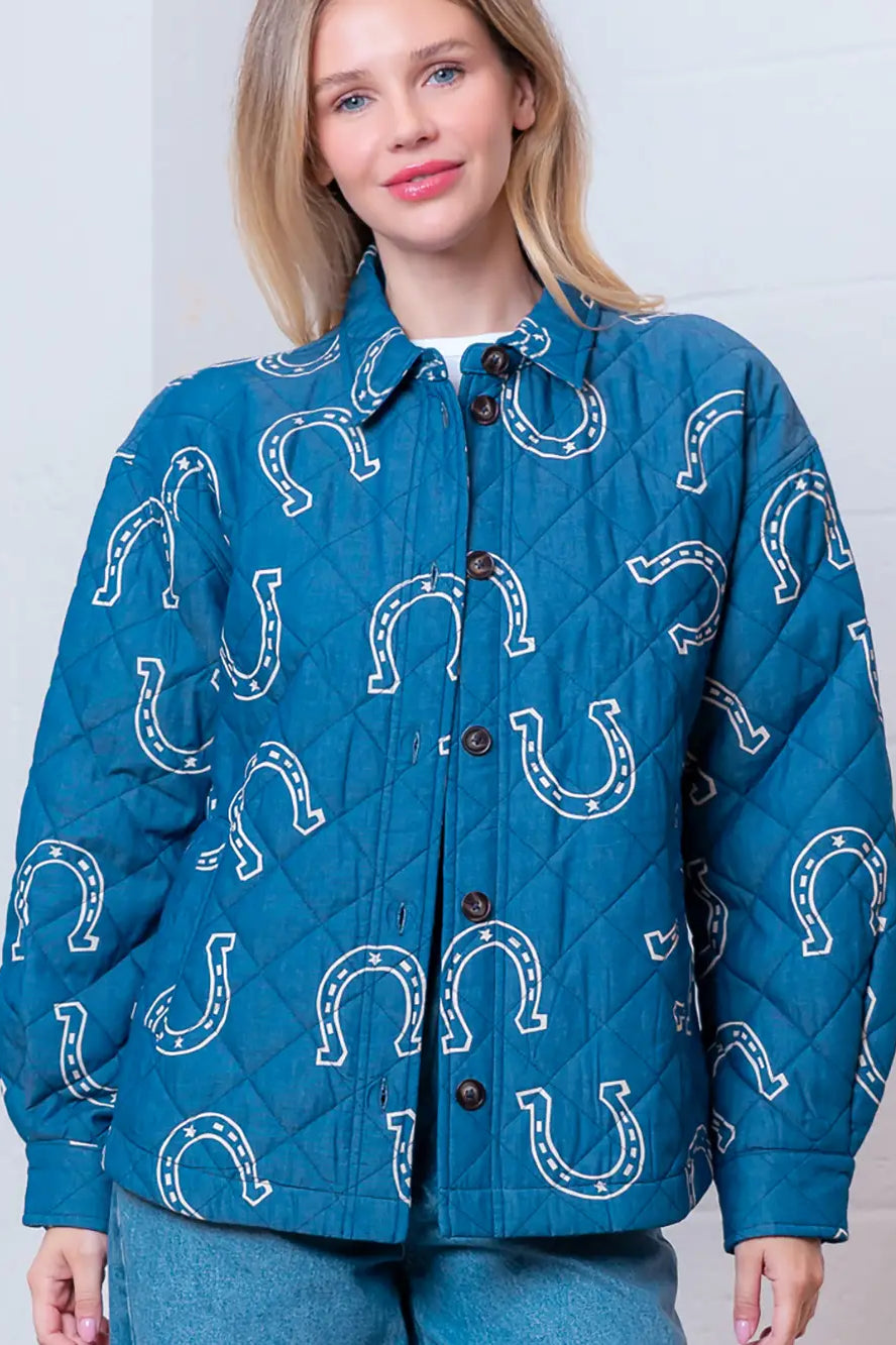 Front view of denim-blue quilted jacket with white horseshoe print and button front on model.