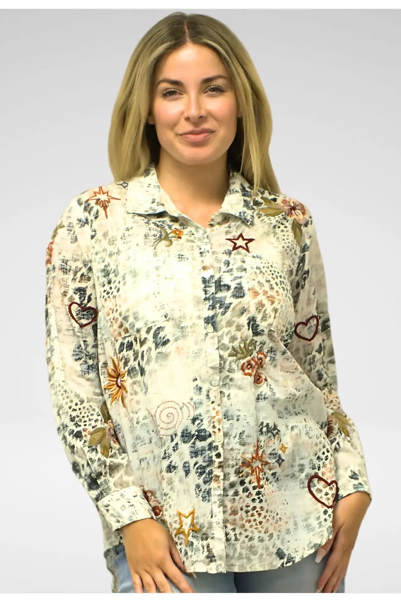 Woman wearing a patterned shirt with various designs on a plain background