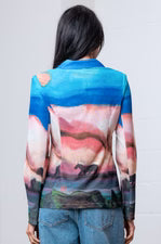 Person wearing a colorful long-sleeve blazer with abstract design on a plain background