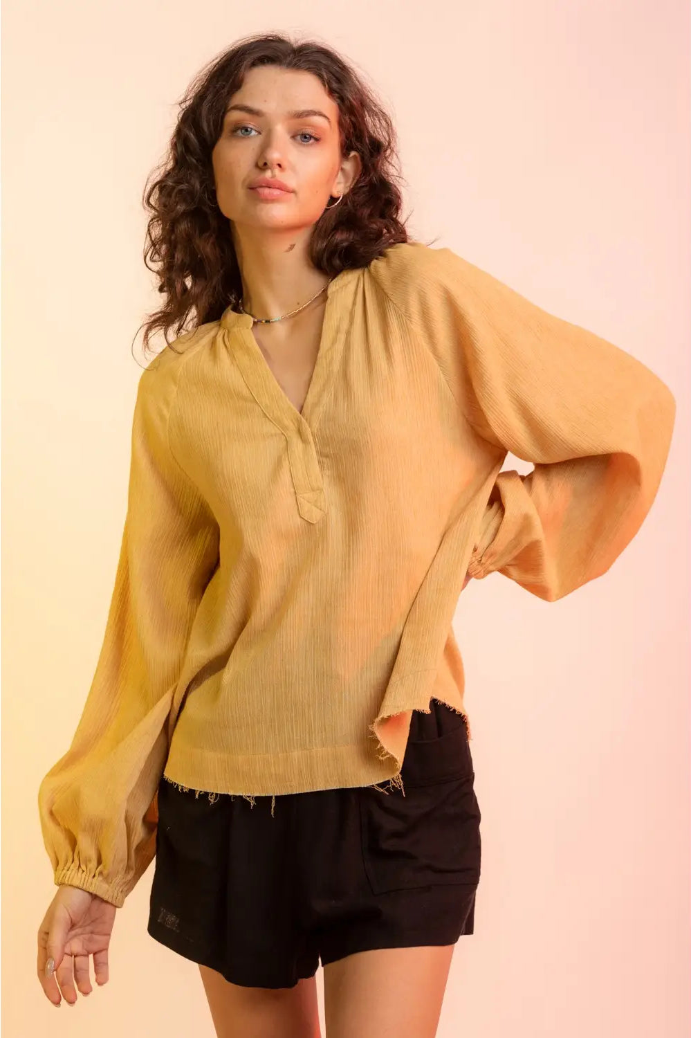 Front view, relaxed pose: Yellow V-neck gauze blouse with raw edge hem and billowy sleeves, model facing camera.