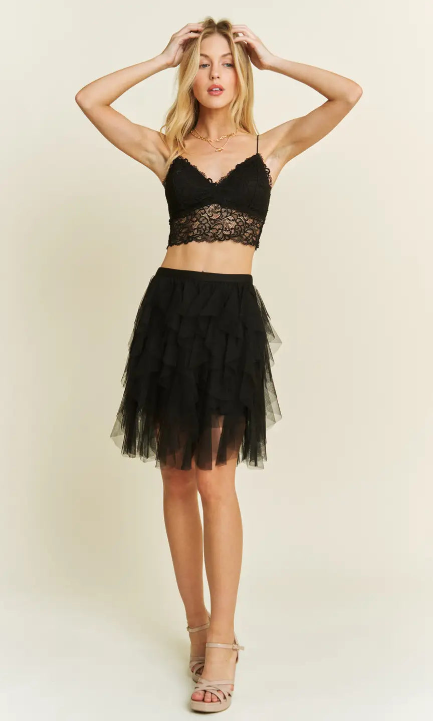 Woman wearing a black mesh layered skirt set on a plain background