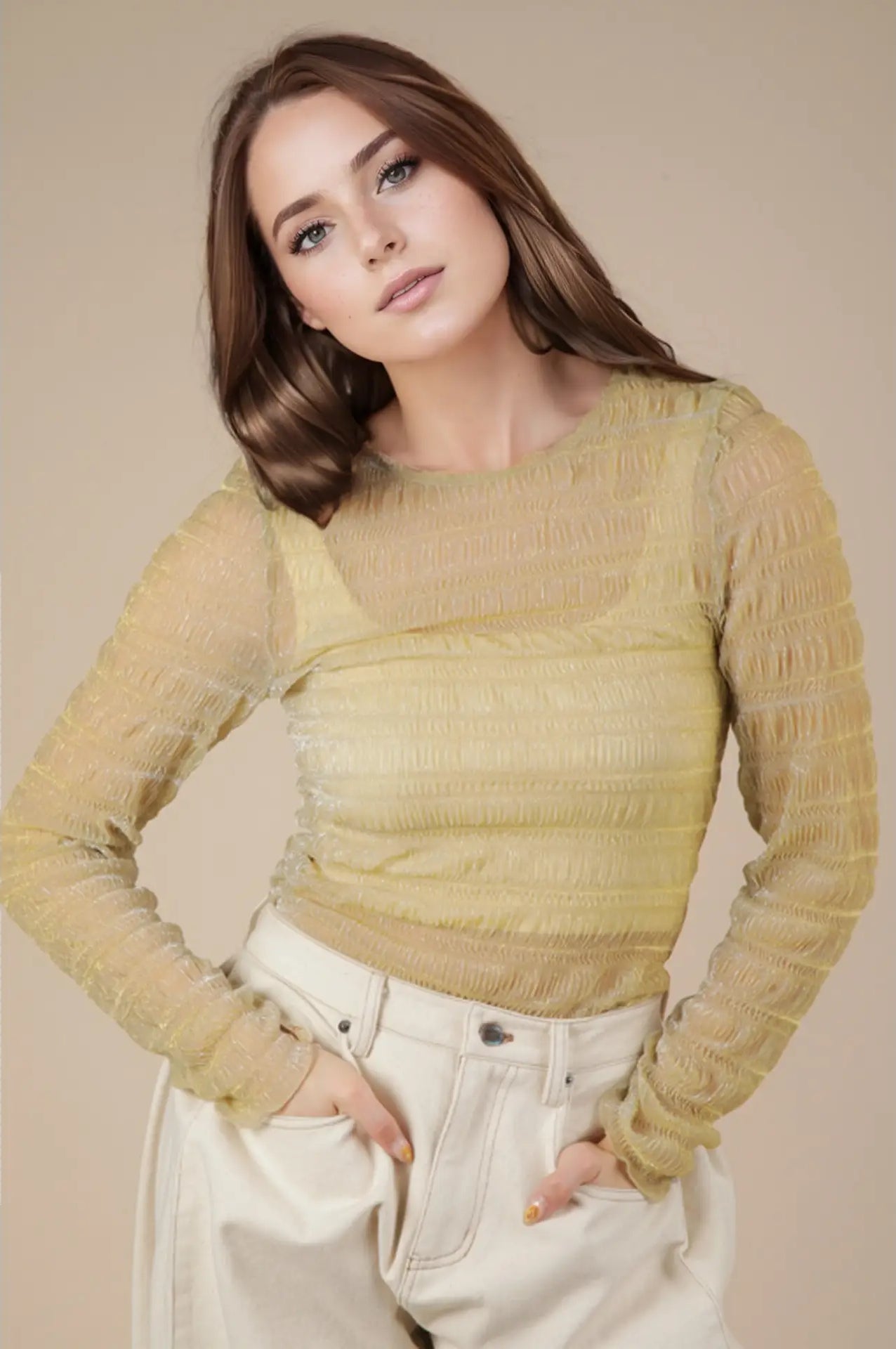 Front view: Model wearing champagne sheer lurex long-sleeve fitted top with crew/mock neck; subtle sparkle visible.