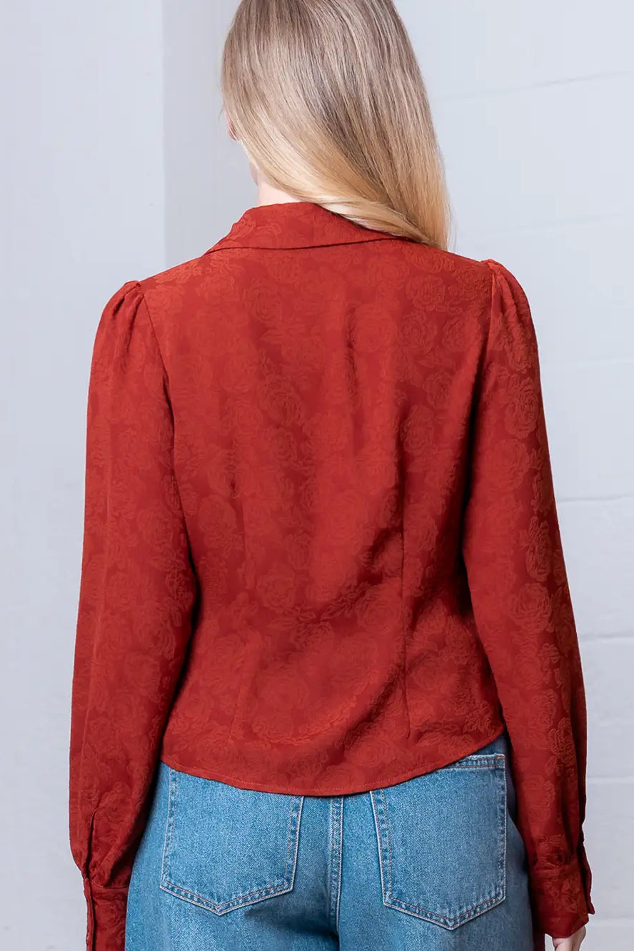 Back view of rust floral-embossed blouse showing shoulder yoke and relaxed drape.