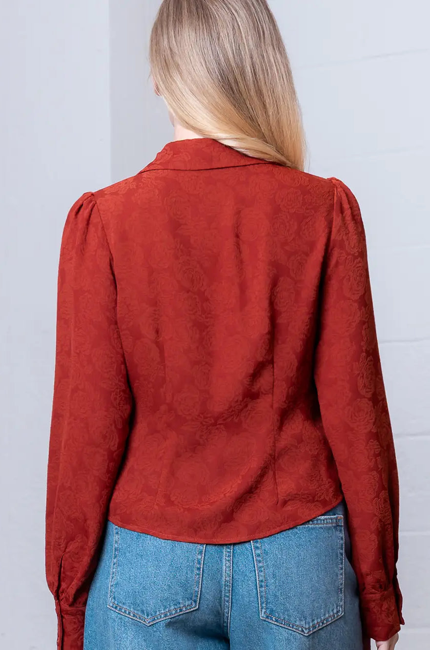 Back view of rust floral-embossed blouse showing shoulder yoke and relaxed drape.
