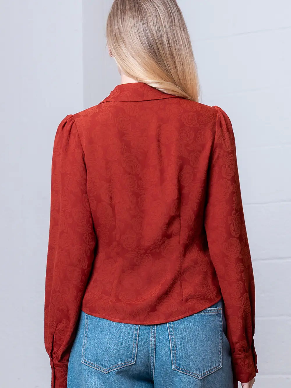 Back view of rust floral-embossed blouse showing shoulder yoke and relaxed drape.