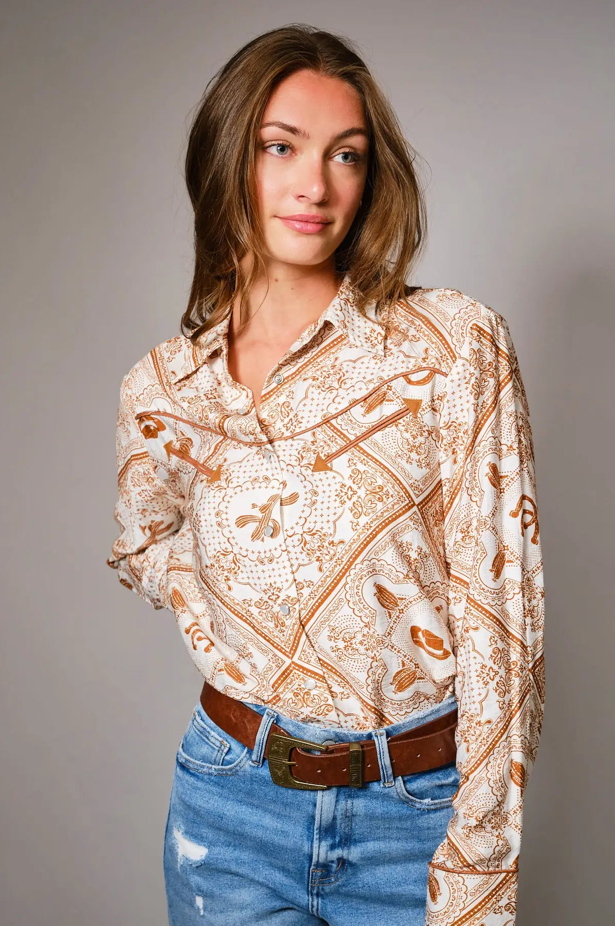 Woman wearing a western patterned blouse western color details snap shirt and jeans