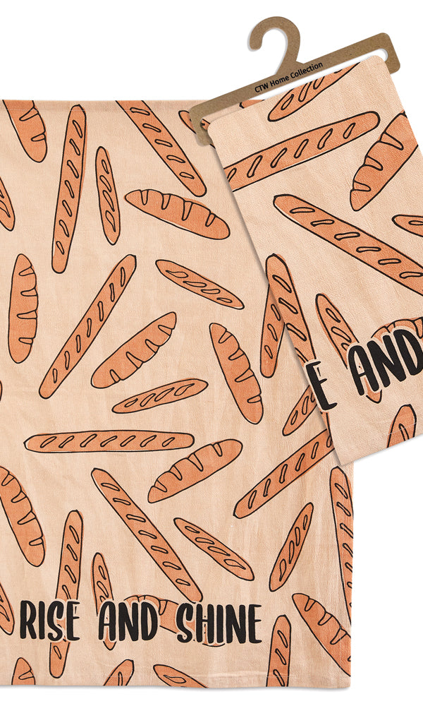 Tea towel with loaves of bread and the words Rise and Shine on a beige background sitting on a white table