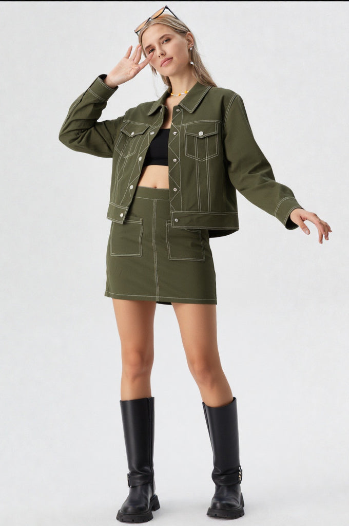 Woman wearing a green jacket and skirt set with black boots on a white background