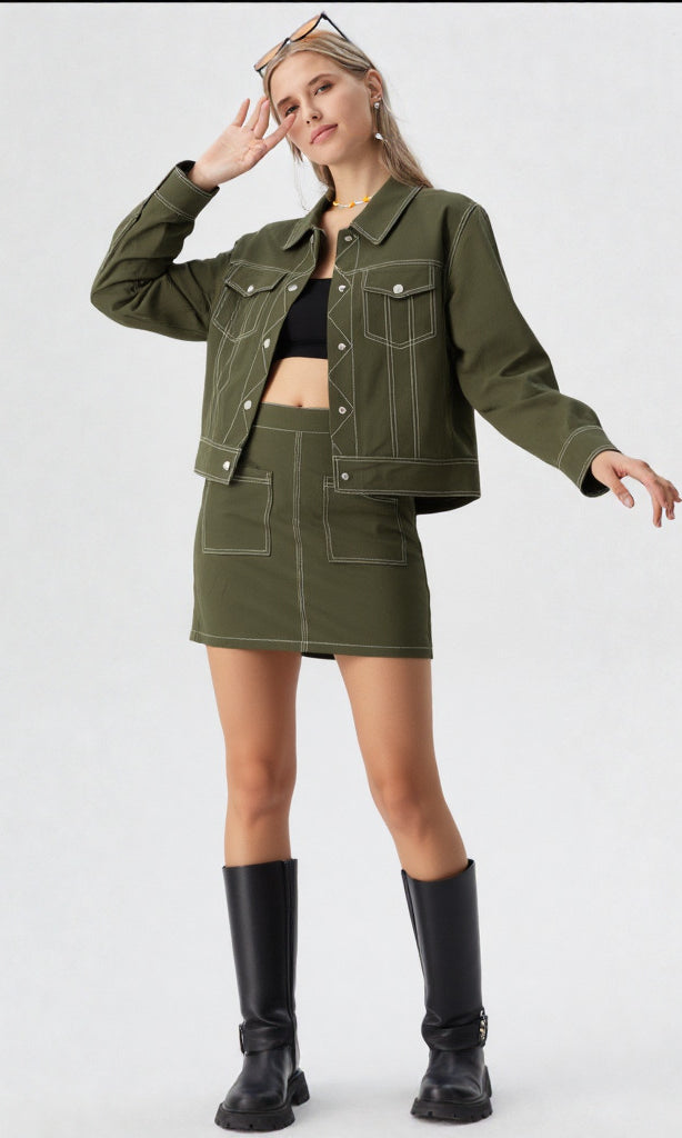 Woman wearing a green jacket and skirt set with black boots on a white background