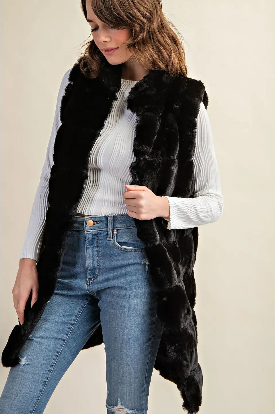 Woman wearing a black fur vest over a white sweater Knee length with pockets