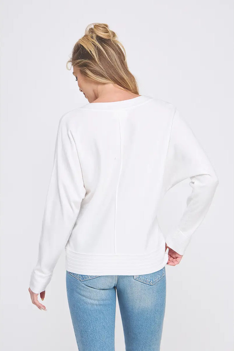 Person wearing a white sweatshirt and blue jeans on a light gray background