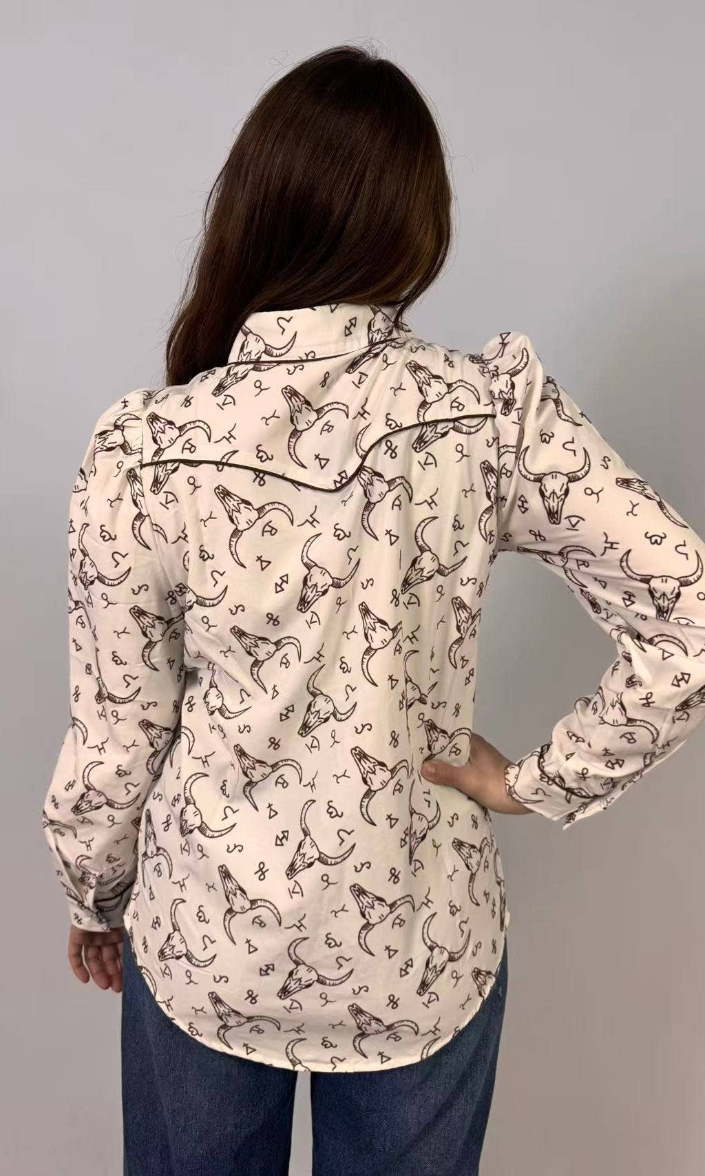 Person wearing a patterned shirt with long sleeves on a gray background