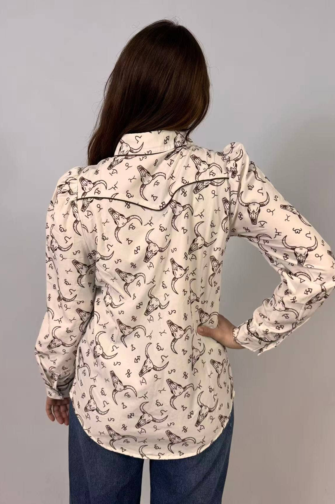 Person wearing a patterned shirt with long sleeves on a gray background