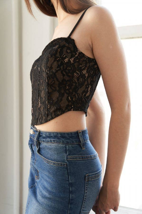 Person wearing a black lace top and blue jeans indoors.