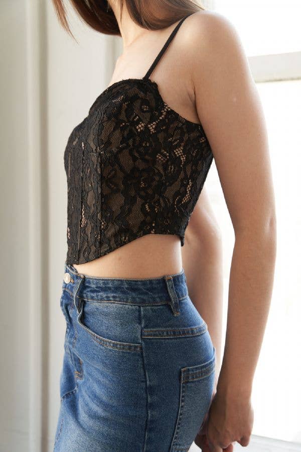 Person wearing a black lace top and blue jeans indoors.