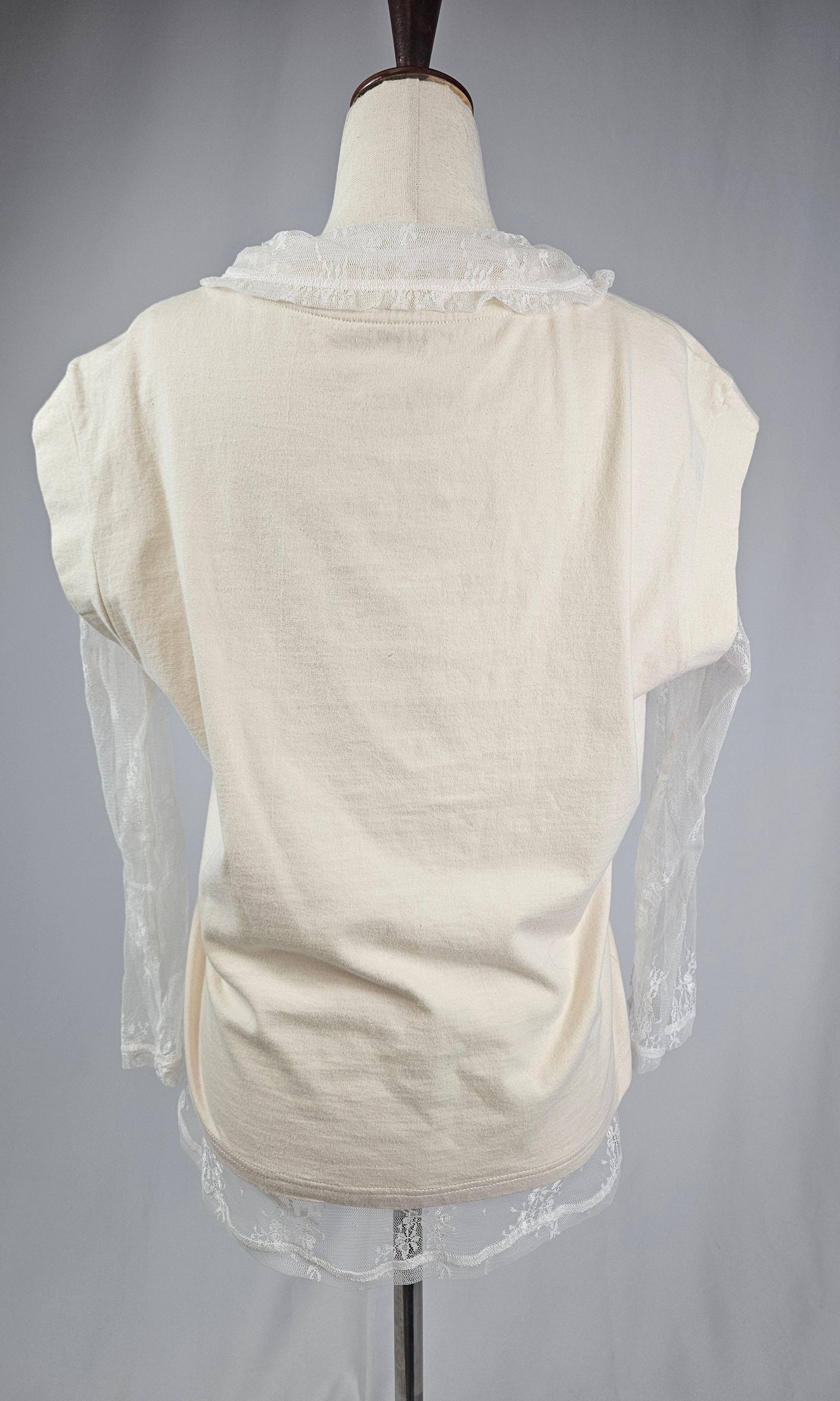 Mannequin wearing a cream-colored top with sheer sleeves and lace details on a gray background