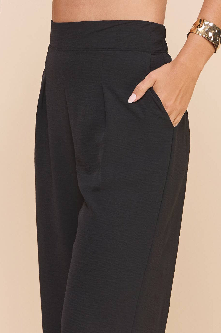 Black wide-leg pants worn by a person on a beige background