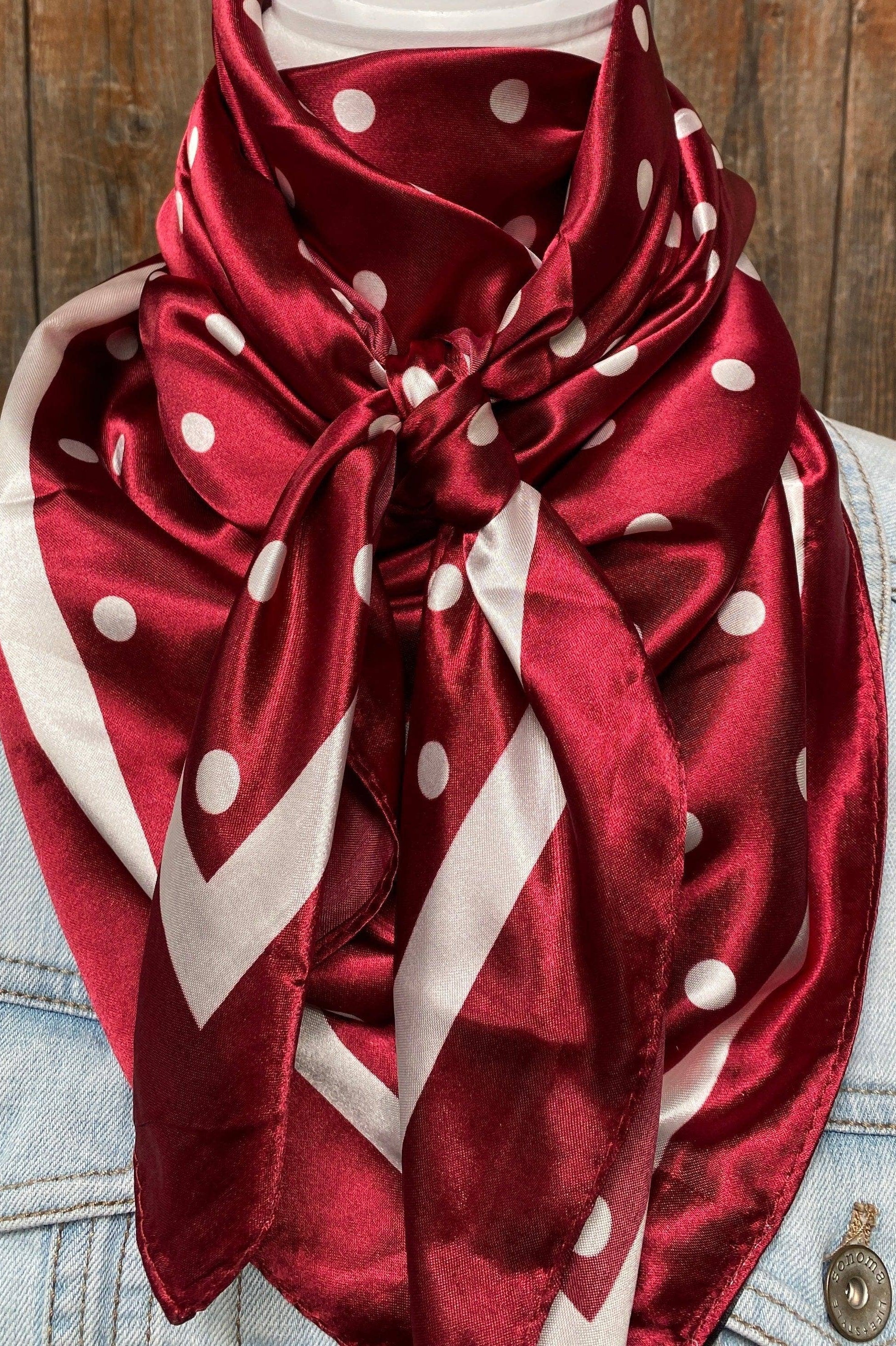 Red polka dot scarf worn by a person with a denim jacket against a wooden background