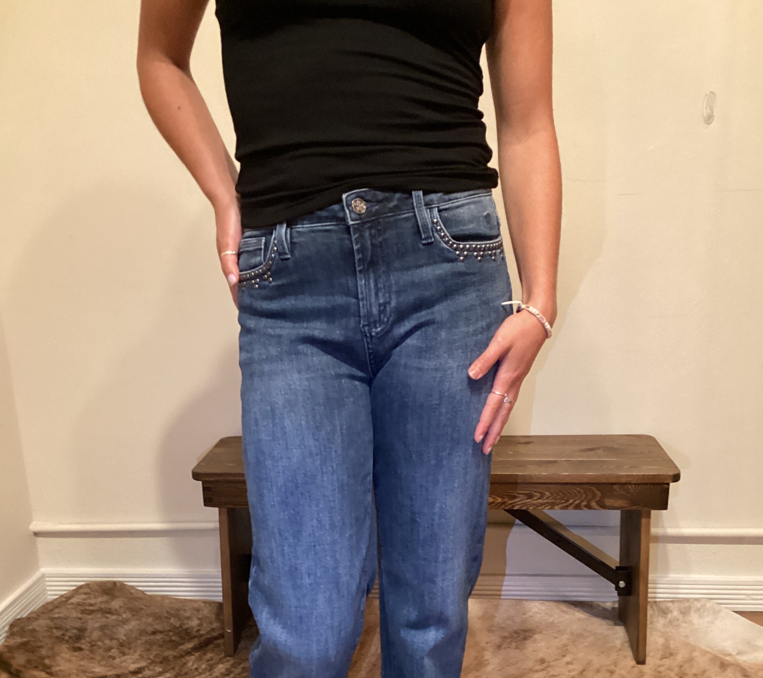 Person wearing blue jeans with stud detailing on the edge of the front pockets